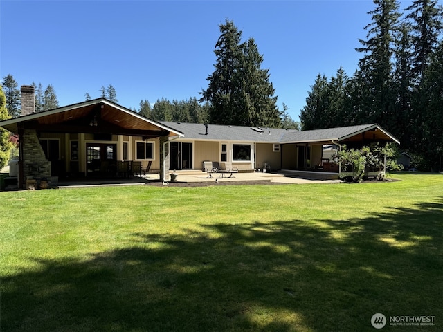 back of house with a chimney, a patio, and a lawn