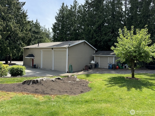 view of side of home with a detached garage, an outdoor structure, and a lawn