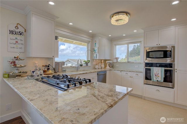 1005 346th Pl, Ocean Park, WA 98640 - kitchen with stainless steel appliances, a peninsula, a sink, crown molding, and white cabinets