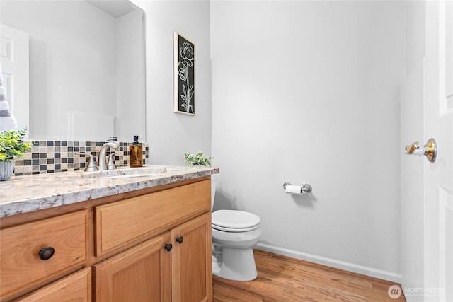 1725 Harrison Pl Unit 103, Lynden, WA 98264 - bathroom featuring toilet, vanity, wood finished floors, baseboards, and decorative backsplash