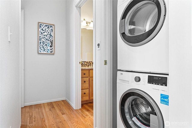 1725 Harrison Pl Unit 103, Lynden, WA 98264 - washroom with estacked washer and dryer, light wood finished floors, and baseboards