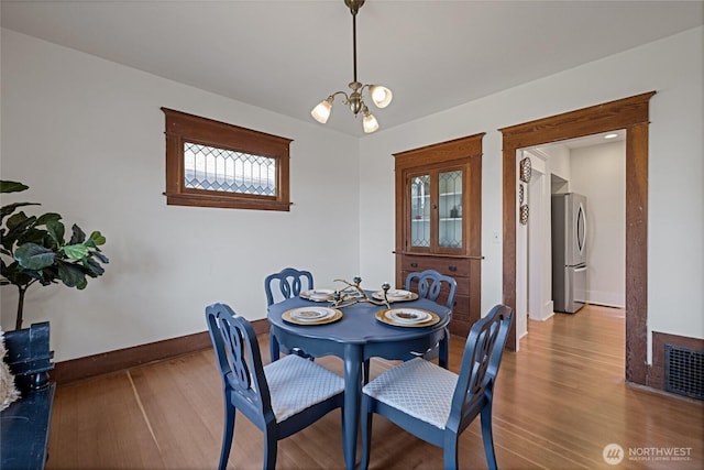 3301 Mckinley Ave, Tacoma, WA 98404 - dining area featuring baseboards, a notable chandelier, visible vents, and wood finished floors