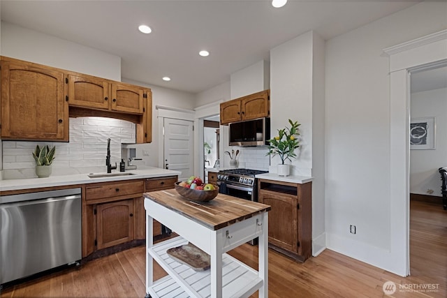 3301 Mckinley Ave, Tacoma, WA 98404 - kitchen featuring light wood-type flooring, decorative backsplash, stainless steel appliances, and a sink