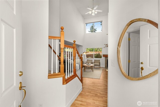 foyer featuring a high ceiling, wood finished floors, baseboards, ceiling fan, and stairs