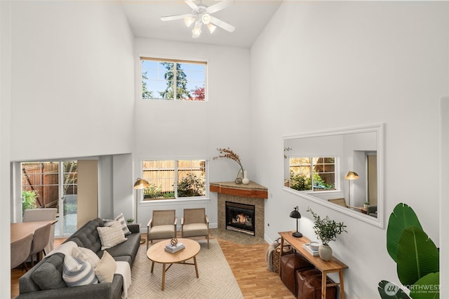 living area with a towering ceiling, ceiling fan, and a fireplace with flush hearth