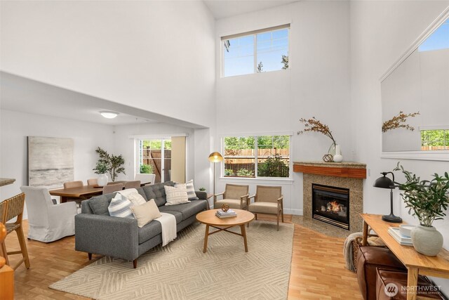 living area with a high ceiling, plenty of natural light, and a tile fireplace