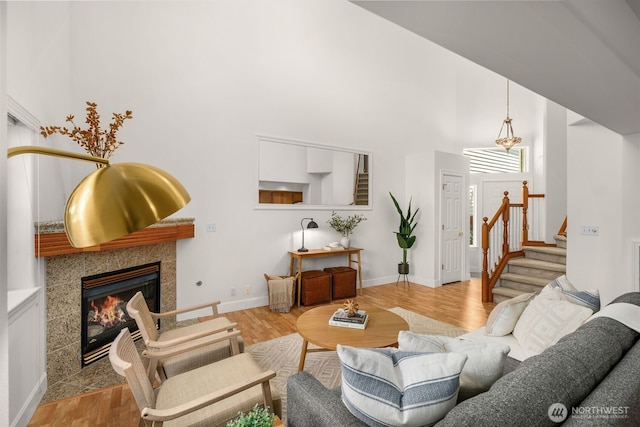 living room with a tile fireplace, stairway, wood finished floors, a high ceiling, and baseboards