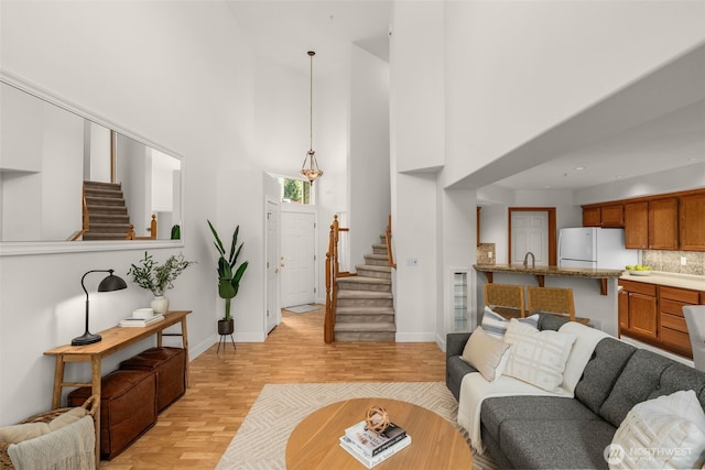 living area with stairway, a high ceiling, light wood finished floors, and baseboards
