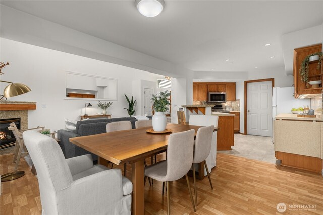 dining space featuring a glass covered fireplace, light wood-style floors, and recessed lighting
