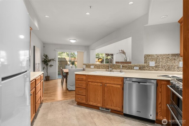 kitchen featuring appliances with stainless steel finishes, a sink, a peninsula, light countertops, and recessed lighting