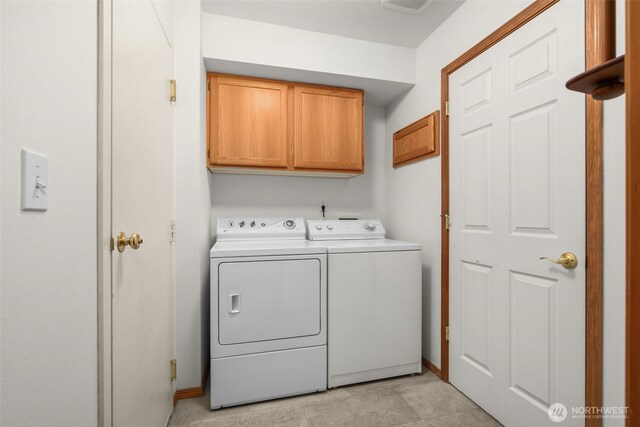 washroom featuring cabinet space, washer and clothes dryer, and baseboards