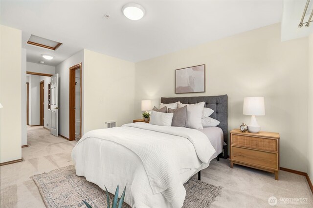 bedroom with attic access, light carpet, and baseboards
