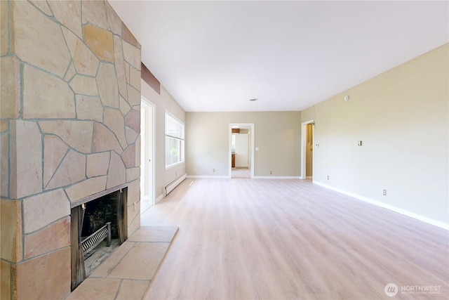 unfurnished living room with light wood-style floors, baseboards, a baseboard radiator, and a fireplace