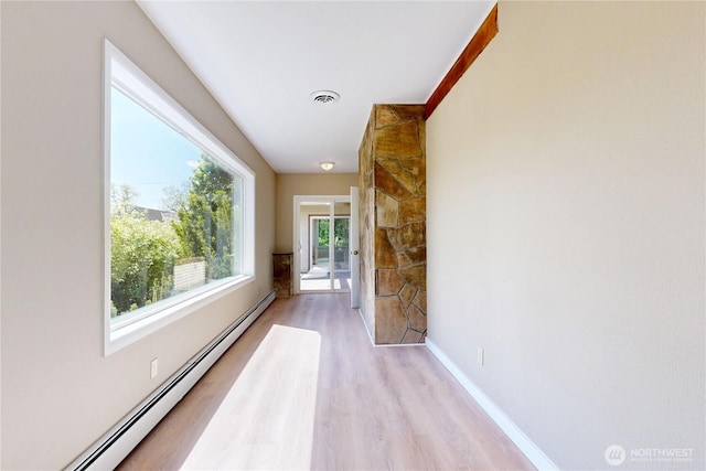 hallway featuring baseboards, light wood-type flooring, baseboard heating, and visible vents