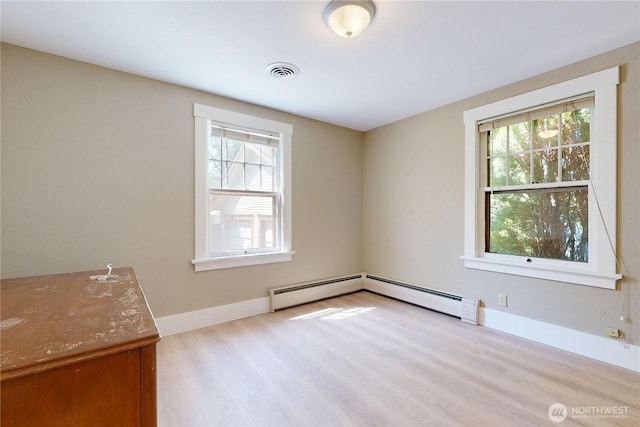 unfurnished room with a baseboard radiator, a healthy amount of sunlight, visible vents, and wood finished floors