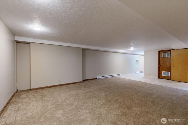 finished basement with a baseboard radiator, baseboard heating, visible vents, and carpet