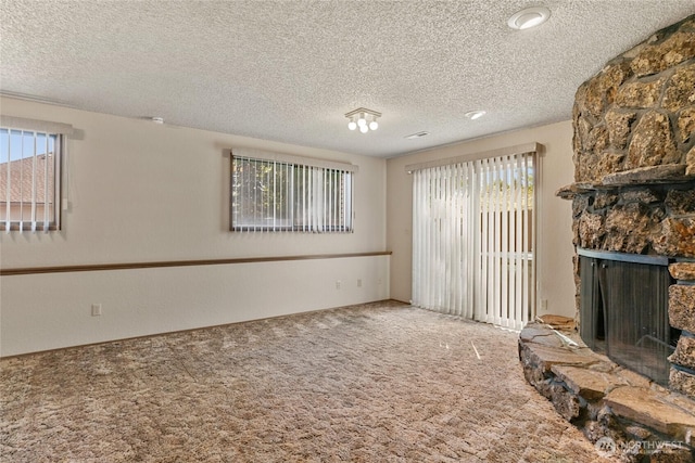 unfurnished living room with a fireplace, a textured ceiling, and carpet