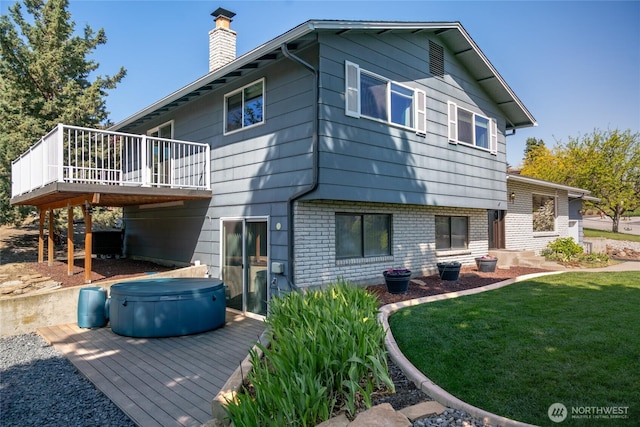 back of property featuring a hot tub, a deck, brick siding, a yard, and a chimney