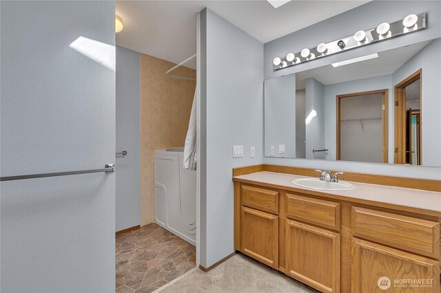 bathroom with washing machine and dryer, a shower, vanity, and baseboards
