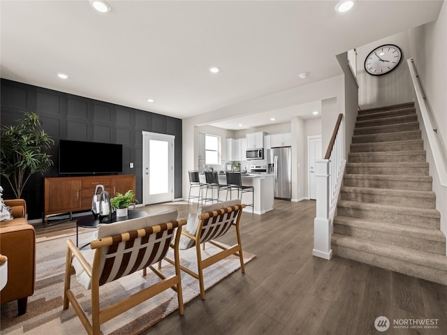 living room featuring stairway, recessed lighting, an accent wall, and wood finished floors