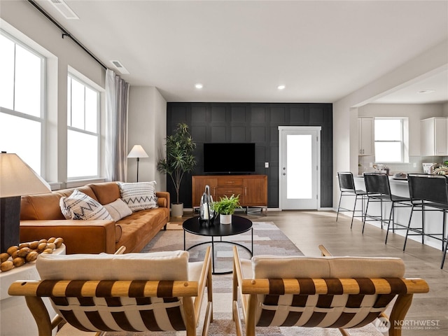 living area with light wood-style floors, visible vents, and recessed lighting