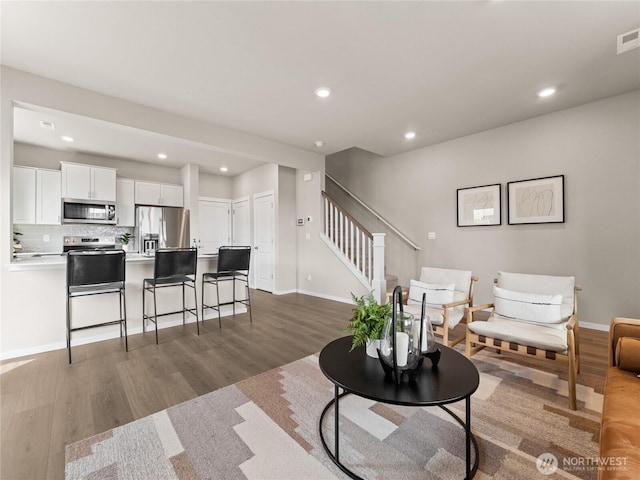 living room with stairway, recessed lighting, baseboards, and wood finished floors