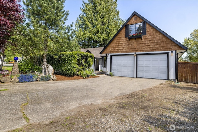 view of front facade with driveway, a garage, and fence