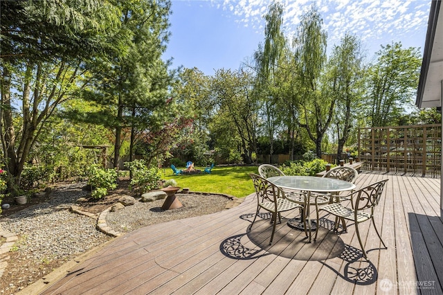 deck featuring outdoor dining area, a playground, and view of scattered trees