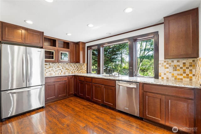 kitchen with appliances with stainless steel finishes, light stone countertops, a sink, decorative backsplash, and recessed lighting