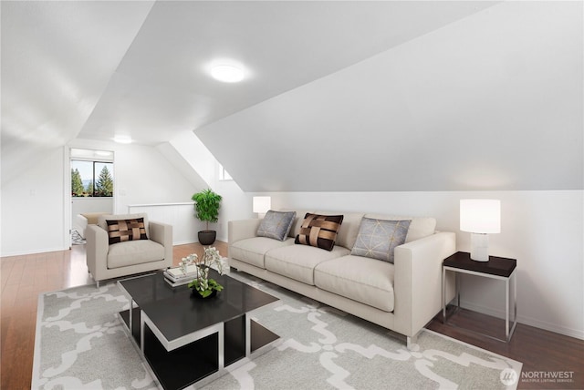 living area featuring wood finished floors, lofted ceiling, and baseboards