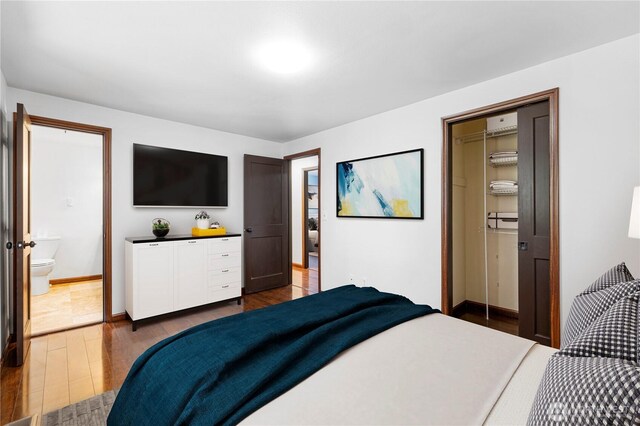 bedroom with dark wood finished floors, baseboards, and ensuite bathroom