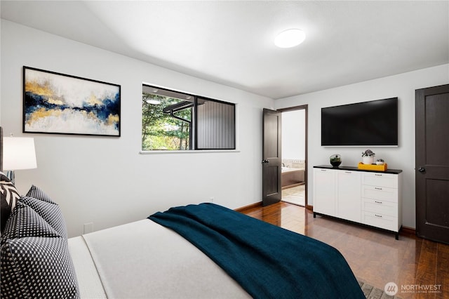 bedroom featuring dark wood-type flooring, baseboards, and ensuite bathroom