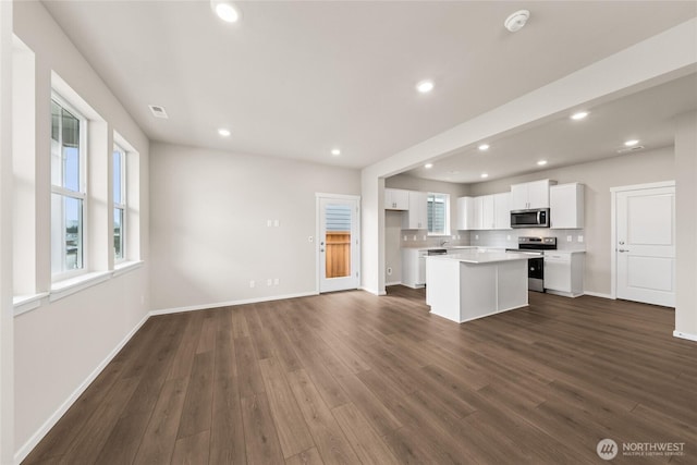 kitchen with dark wood-style flooring, stainless steel appliances, white cabinetry, and a center island