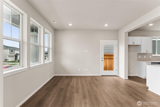 unfurnished living room featuring baseboards, a wealth of natural light, and wood finished floors