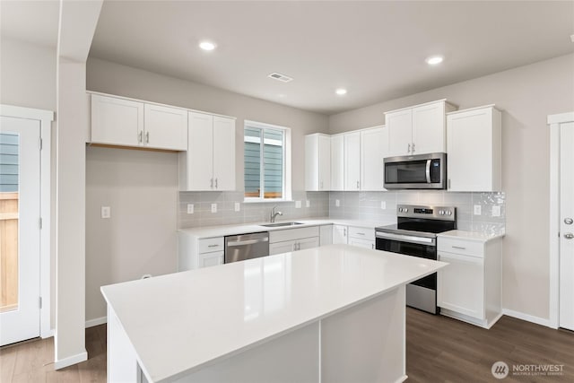 kitchen with a sink, visible vents, white cabinetry, decorative backsplash, and appliances with stainless steel finishes
