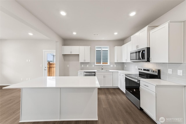 kitchen featuring stainless steel appliances, tasteful backsplash, white cabinets, and recessed lighting