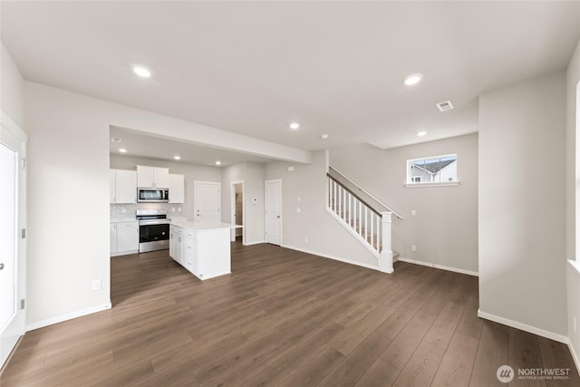 unfurnished living room with recessed lighting, baseboards, visible vents, stairs, and dark wood-type flooring