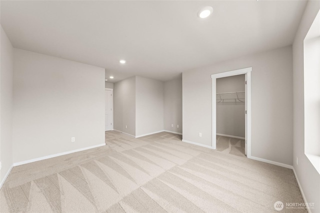 unfurnished bedroom featuring light carpet, baseboards, a spacious closet, and recessed lighting