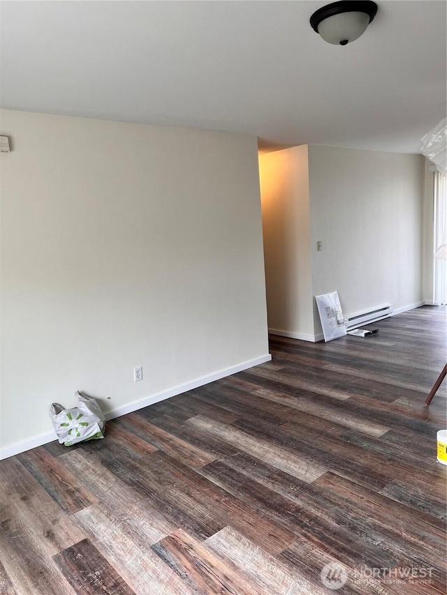 spare room featuring baseboard heating, dark wood-style flooring, and baseboards