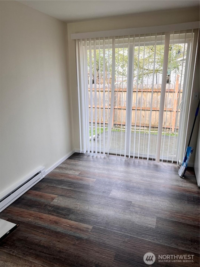 empty room with wood finished floors, baseboards, and a baseboard radiator