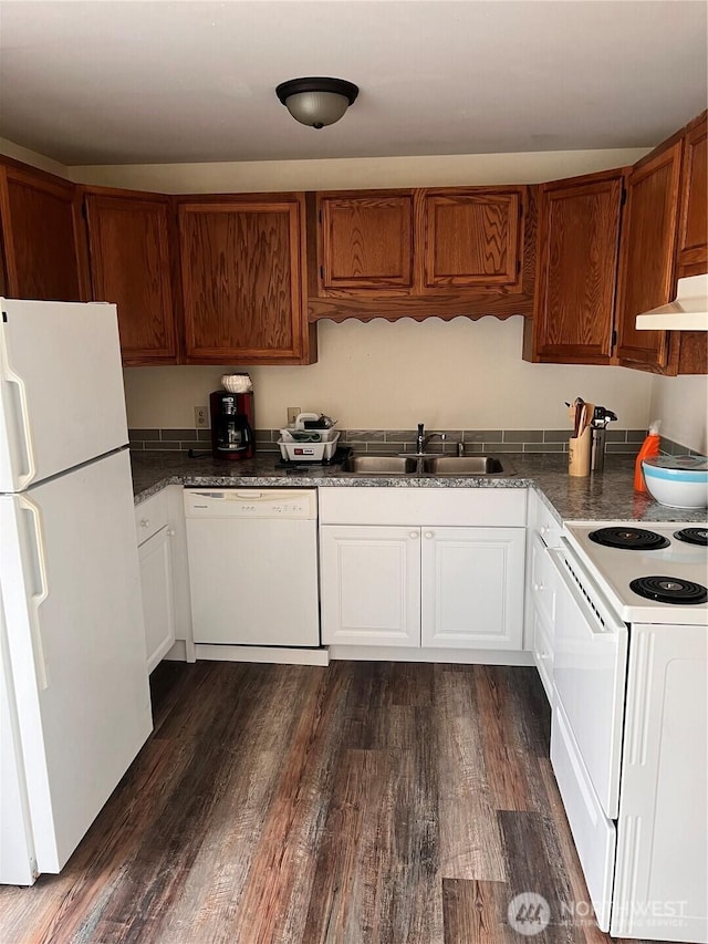 kitchen featuring white appliances, a sink, dark wood-type flooring, and dark countertops