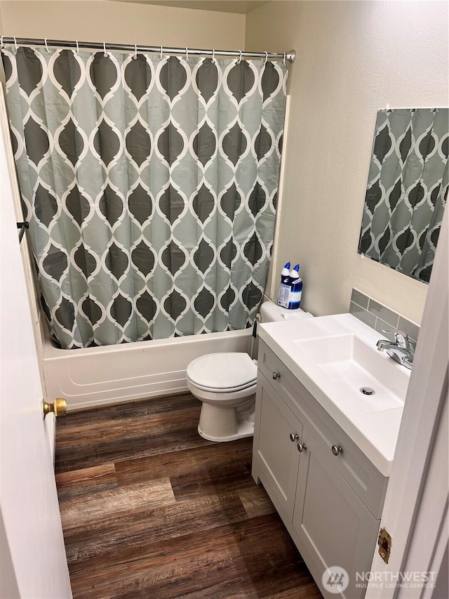 bathroom featuring wood finished floors, shower / tub combo with curtain, toilet, and vanity