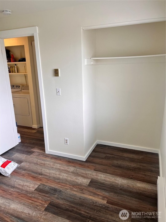 unfurnished bedroom featuring washing machine and clothes dryer, dark wood-type flooring, a baseboard heating unit, and baseboards