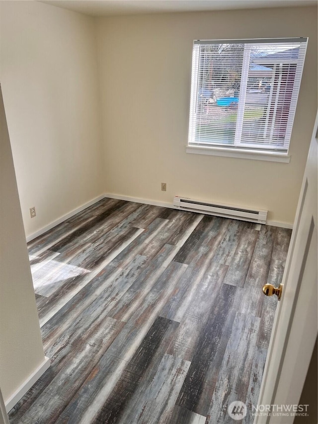 unfurnished room featuring baseboard heating, wood finished floors, and baseboards