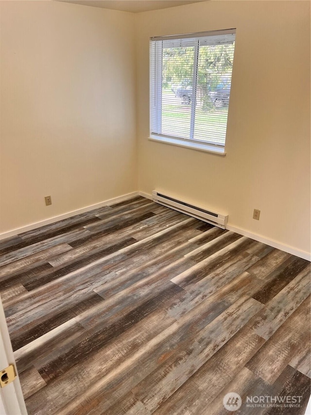 unfurnished room with baseboard heating, dark wood finished floors, and baseboards