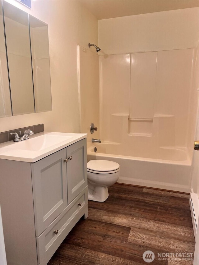 full bath with wood finished floors, toilet, shower / bath combination, vanity, and baseboard heating