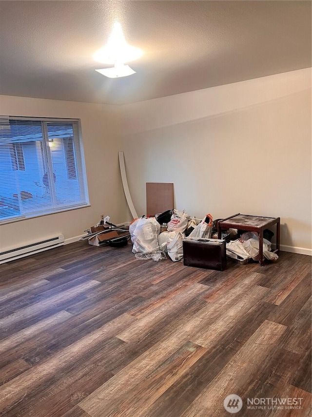 unfurnished room featuring dark wood finished floors, baseboard heating, and baseboards