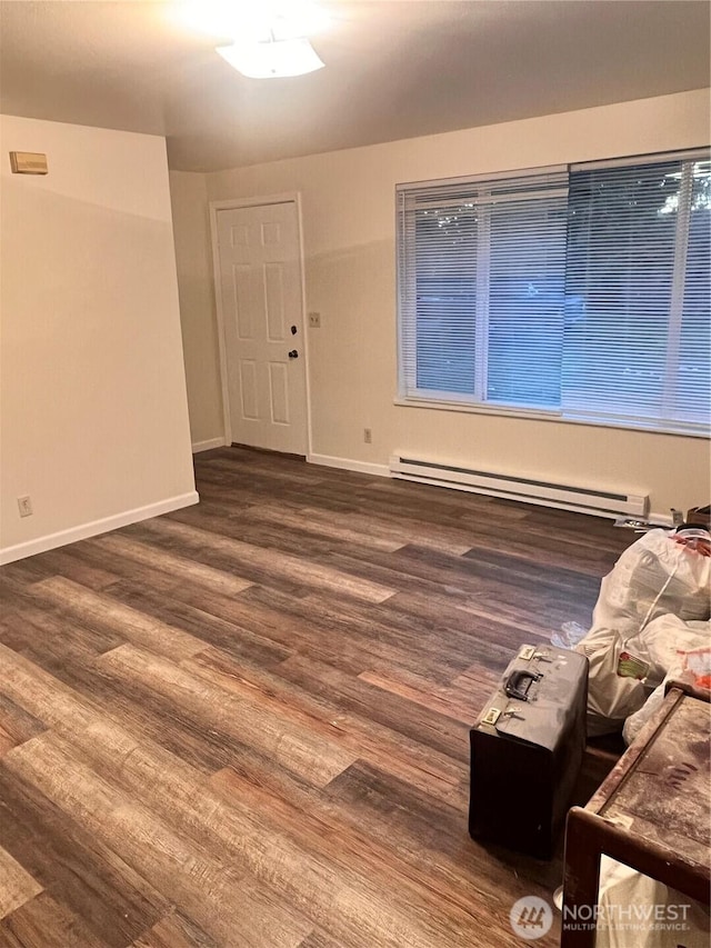 unfurnished room featuring a baseboard radiator, wood finished floors, and baseboards
