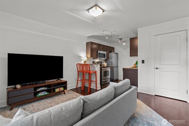 living area featuring baseboards and dark wood-type flooring