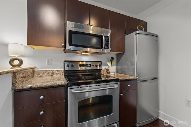 kitchen with dark brown cabinets, stainless steel appliances, and light stone countertops